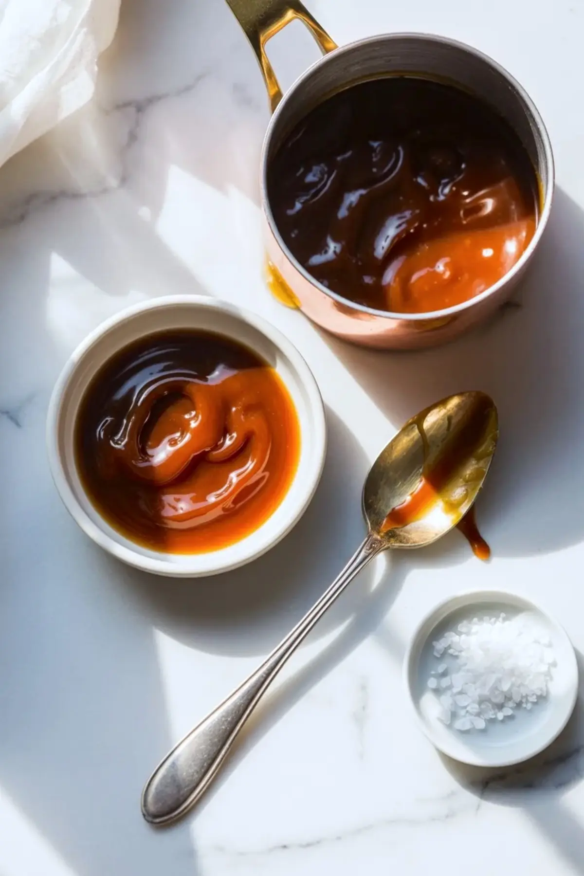 Ingredients for miso caramel cookies arranged overhead with flour, sugars, butter, cream cheese, caramel, cream, vanilla, and white miso on a white marble surface.