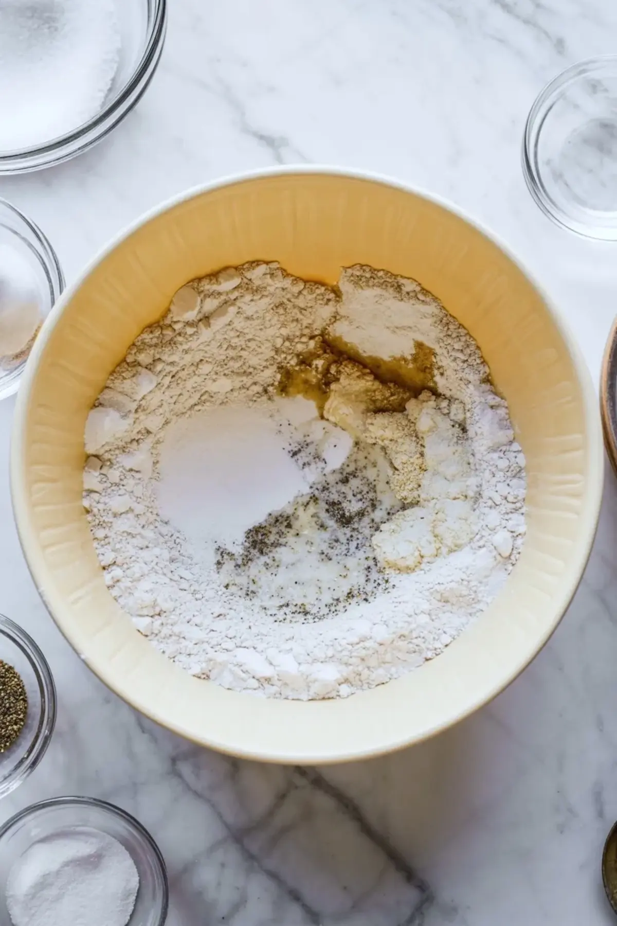 Dry ingredients for sausage breakfast muffins mixed in a bowl with seasonings during the batter preparation stage.