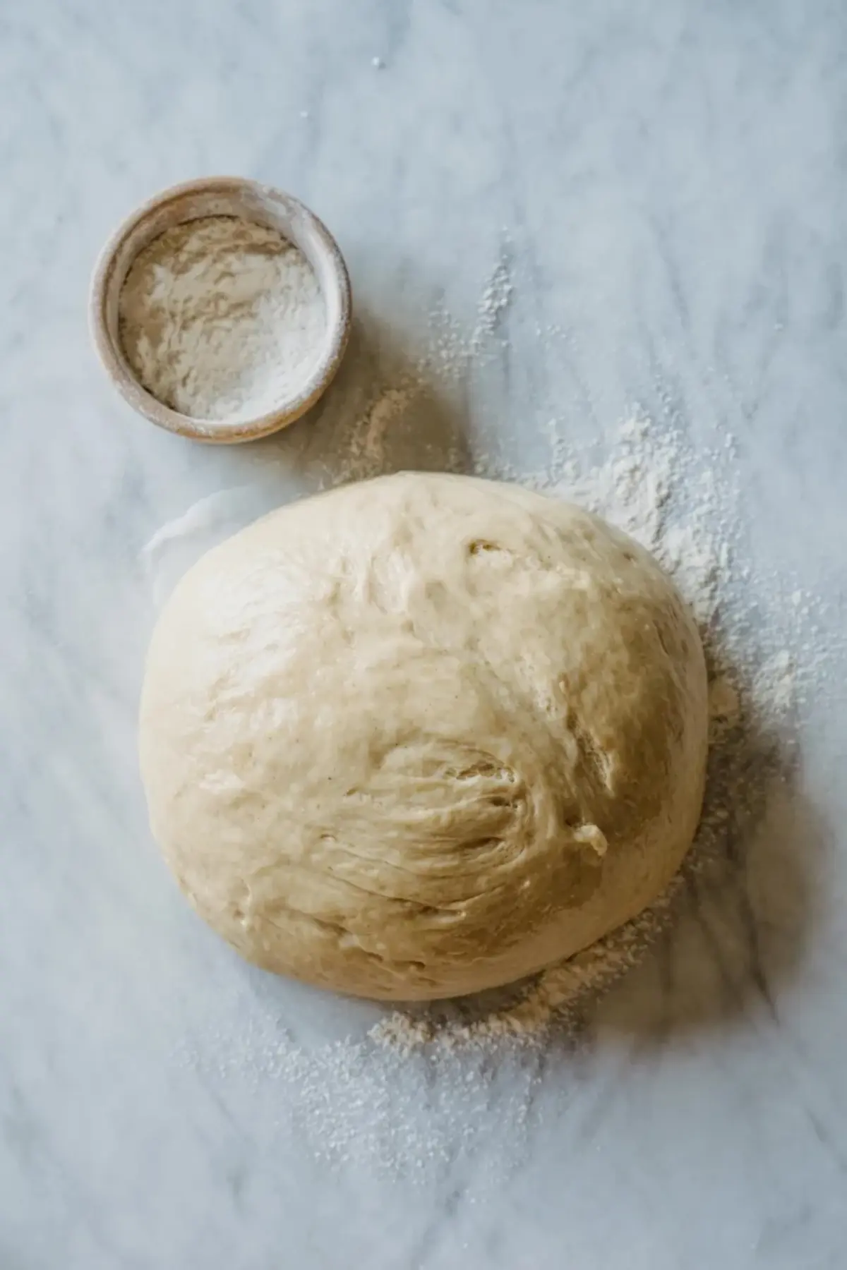Risen sourdough English muffin dough resting on a floured surface before shaping.
