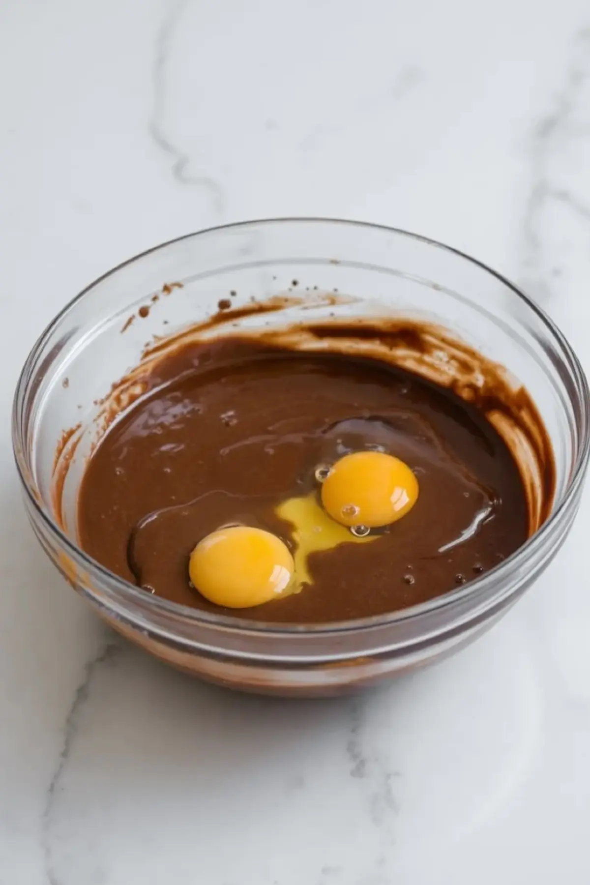 Eggs are added to chocolate brownie batter in a glass bowl while star-spangled brownies are mixed.