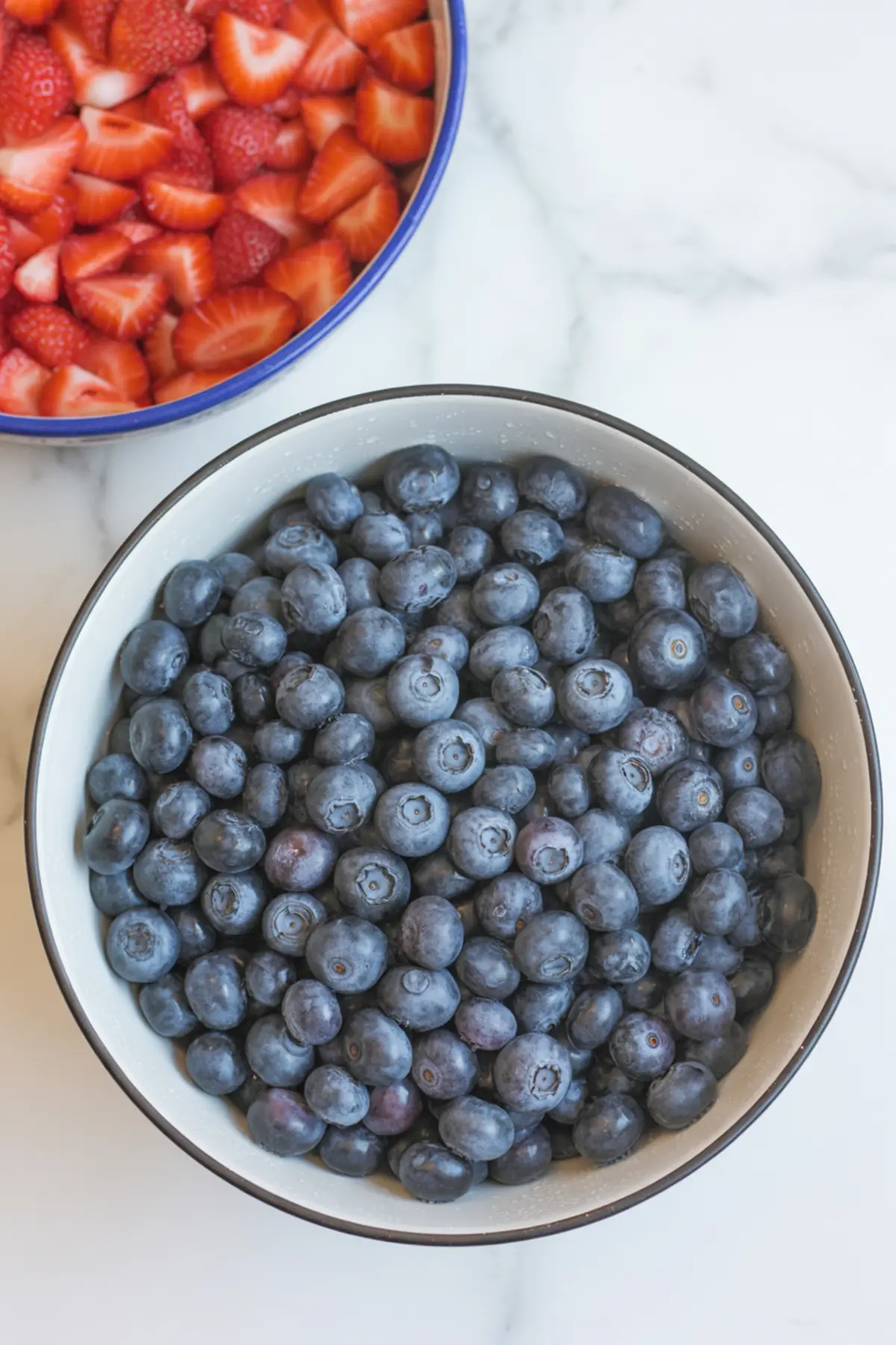 Fresh blueberries and diced strawberries in bowls for a blueberry salsa recipe before mixing.