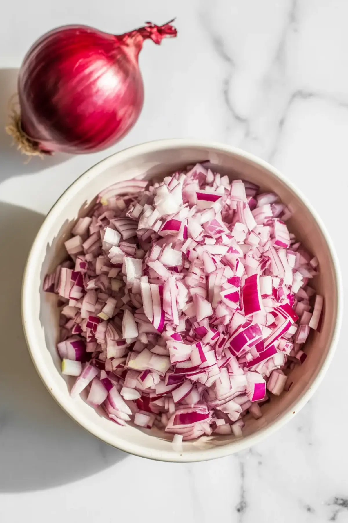 Finely chopped red onion in a bowl for adding sharp crunch to fresh blueberry salsa.
