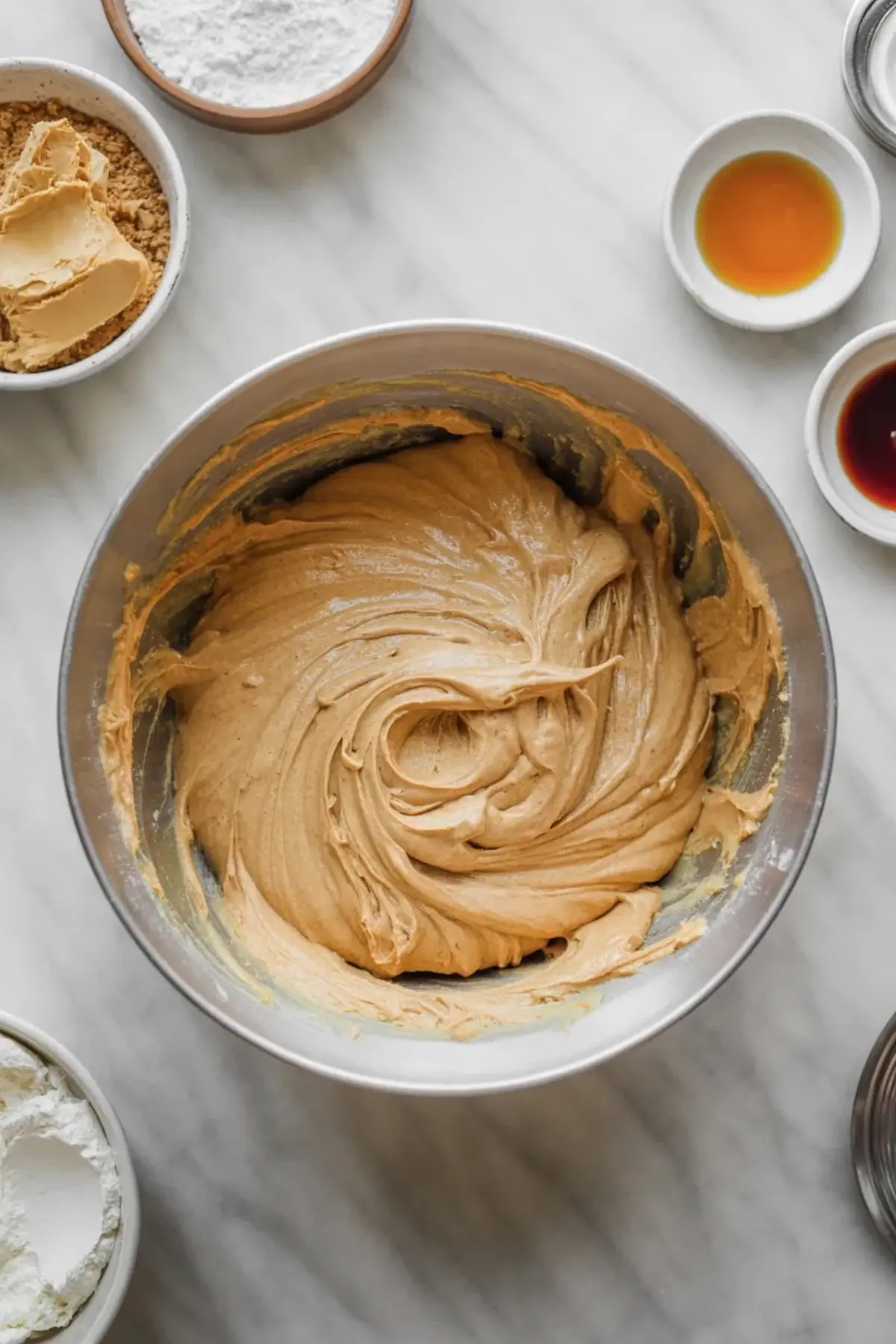 Creamy peanut butter filling mixed in a bowl with baking ingredients nearby for the middle layer of buckeye brownies.