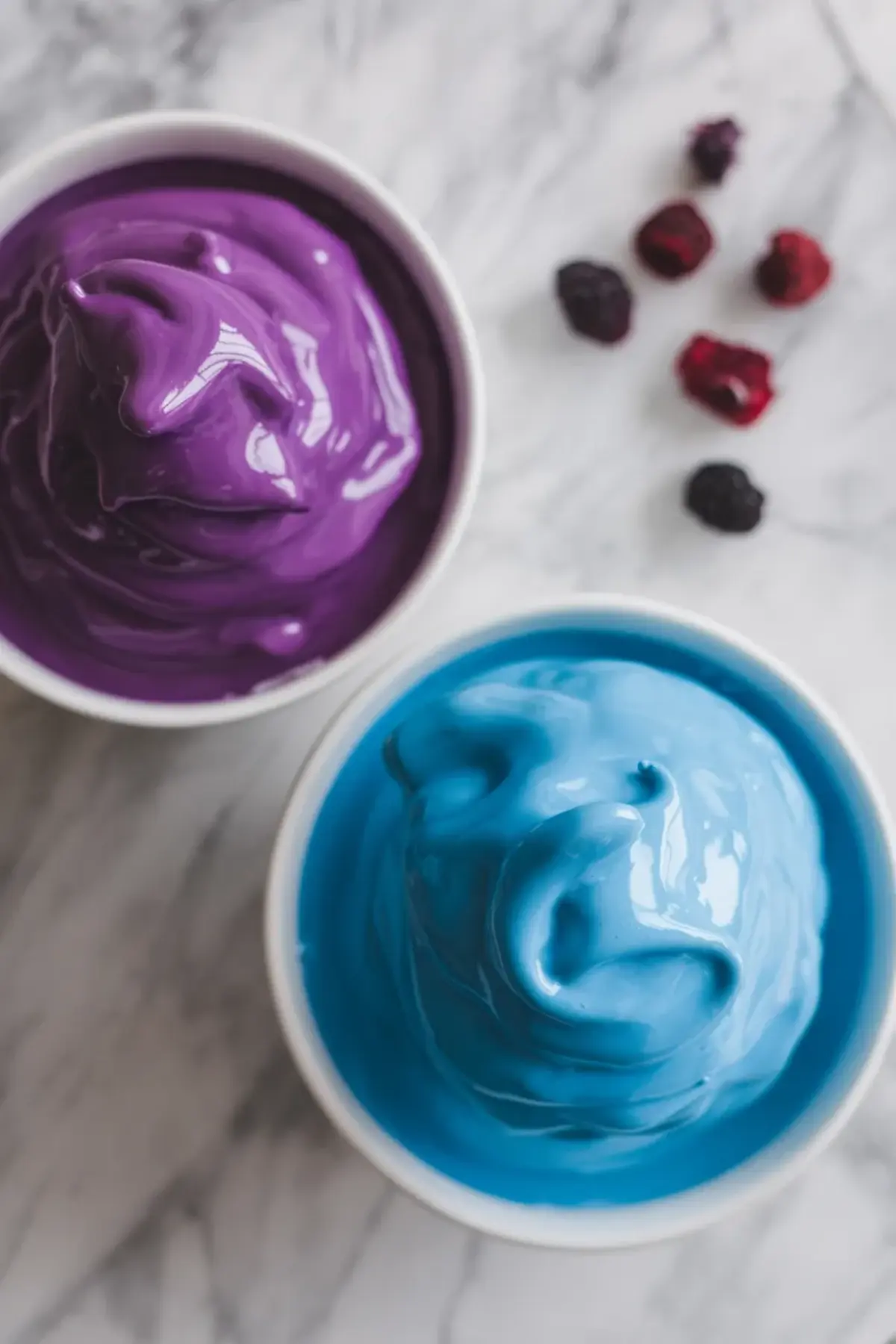 Purple glaze and blue icing in bowls for decorating homemade wild berry Pop Tarts.