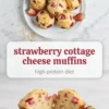 Strawberry cottage cheese muffins on a white plate with fresh strawberries and oats, above a muffin split open to show a soft crumb with pink berry pieces.